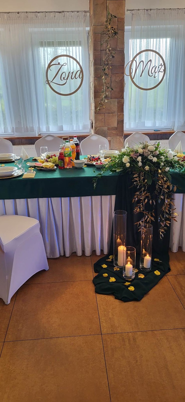 Stół pary młodej z zielono-złotą dekoracją i napisem Żona Mąż